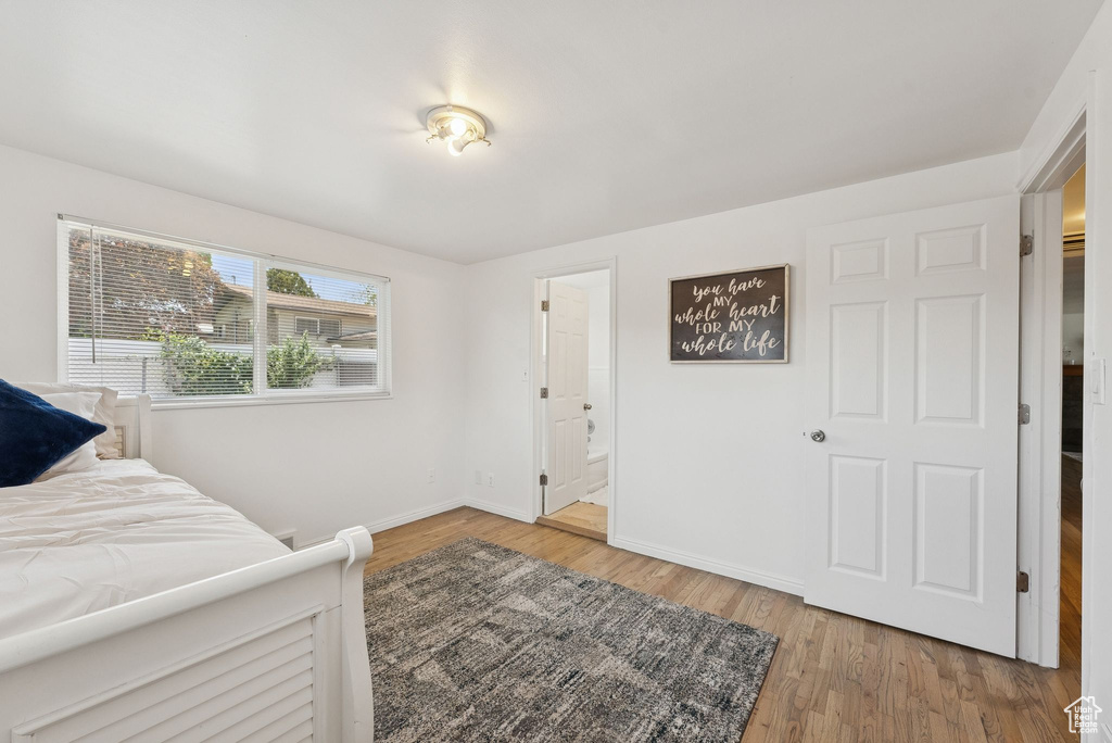 Bedroom with baseboards, wood finished floors, and ensuite bath