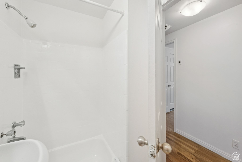 Full bath with a shower, wood finished floors, and baseboards