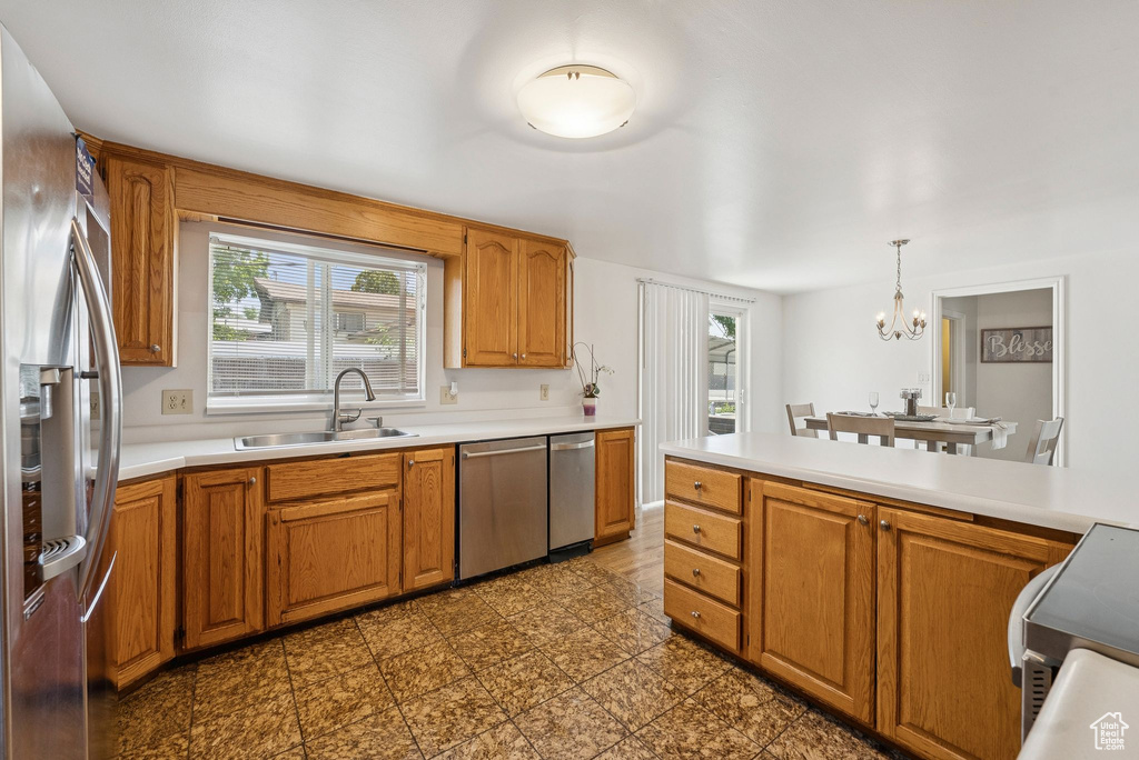 Kitchen with a sink, appliances with stainless steel finishes, a chandelier, and light countertops