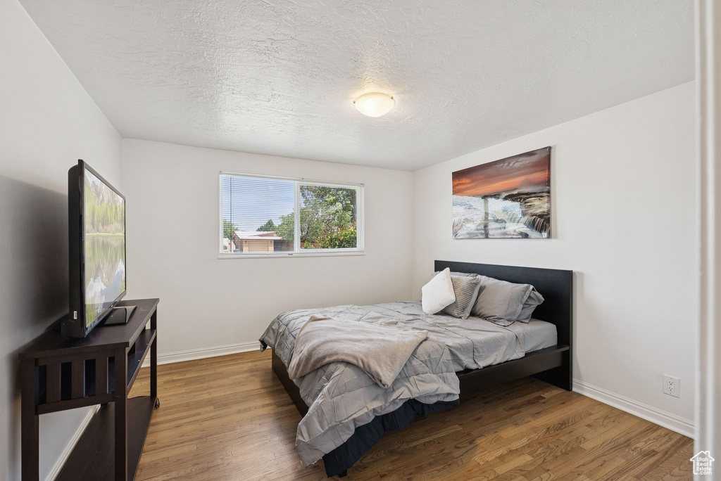 Bedroom with baseboards, wood finished floors, and a textured ceiling