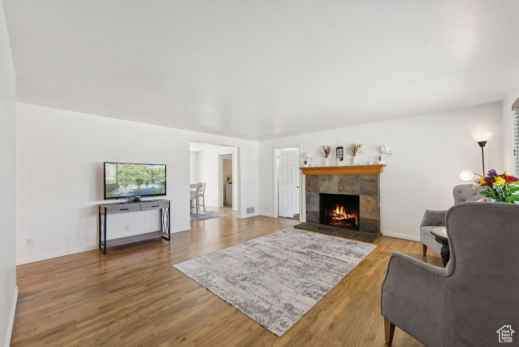 Living area with a fireplace, wood finished floors, and baseboards