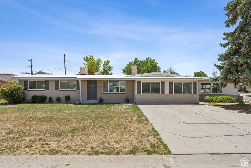 Single story home featuring a chimney, a front lawn, concrete driveway, and brick siding