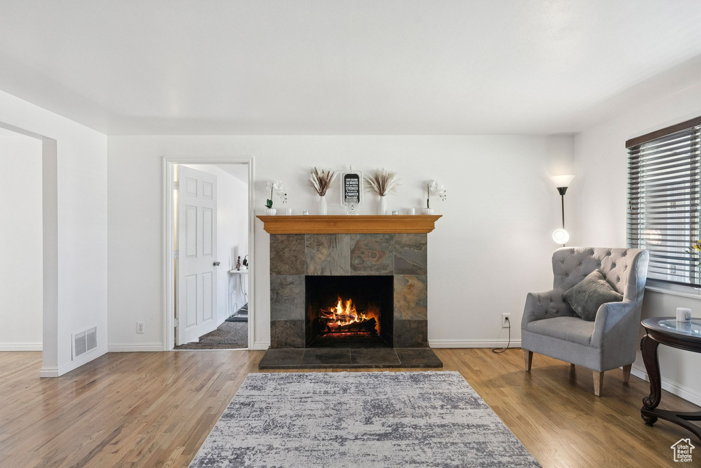 Living area with a tile fireplace, wood finished floors, and baseboards