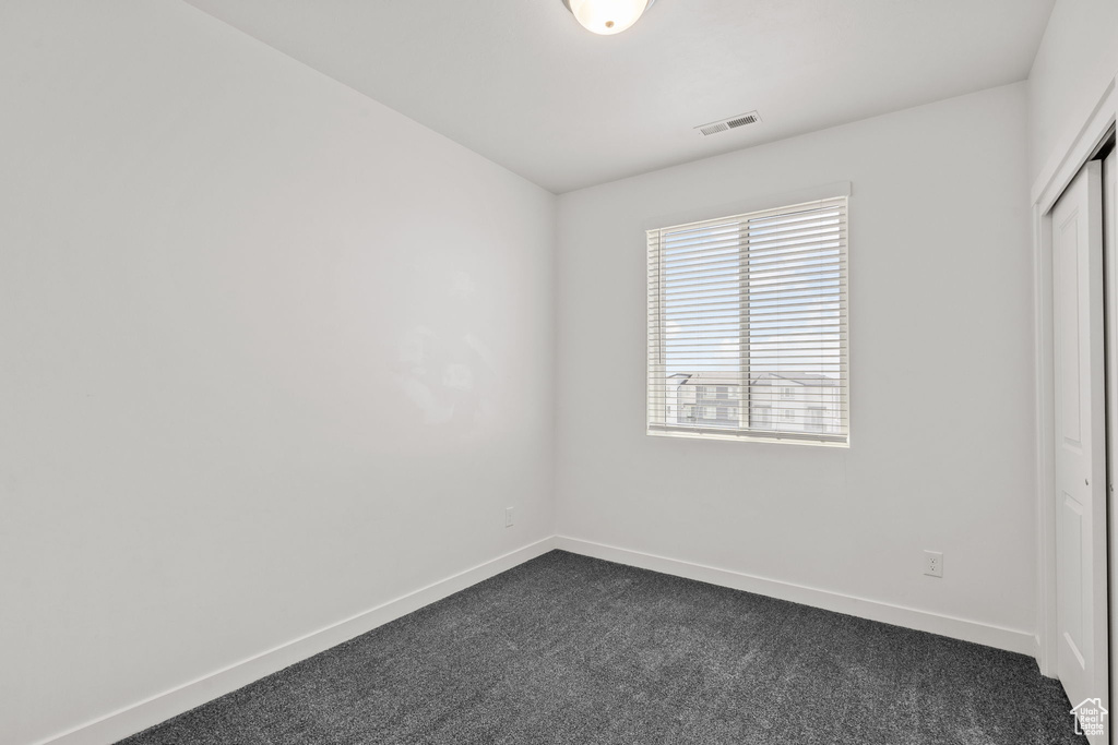 Unfurnished bedroom featuring dark colored carpet, baseboards, and a closet