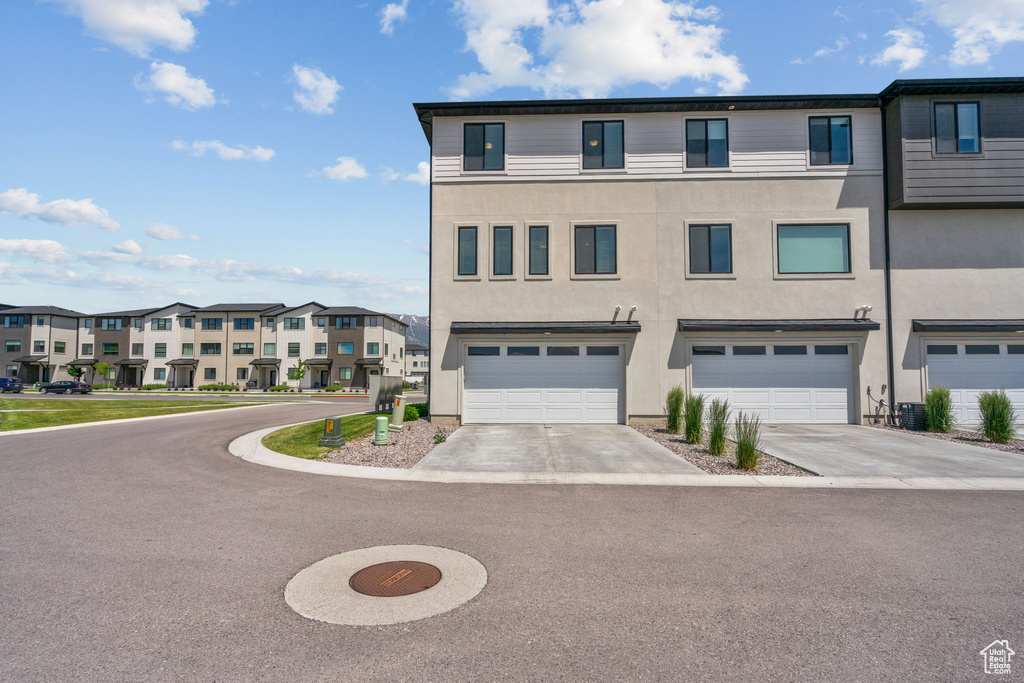 Townhome / multi-family property featuring a residential view, stucco siding, a garage, and concrete driveway