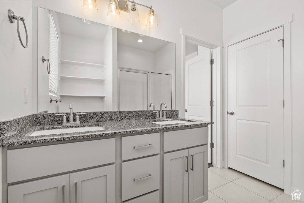 Bathroom with a stall shower, tile patterned floors, and double vanity