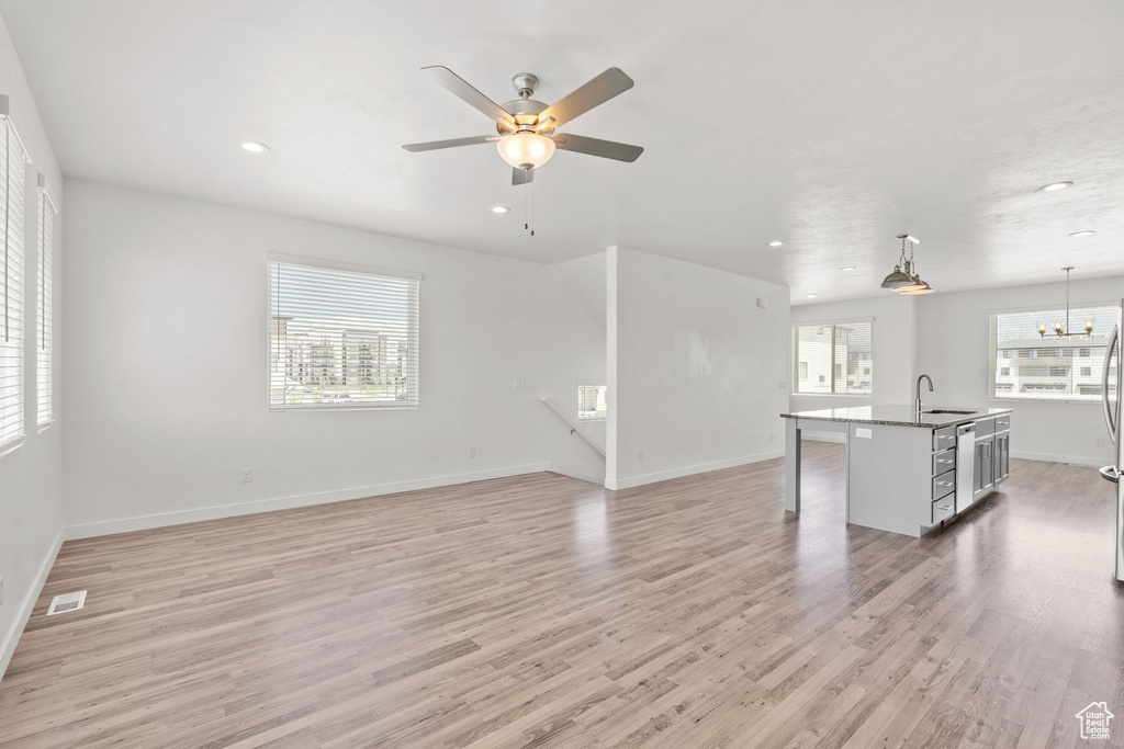 Unfurnished living room with light wood-style floors, ceiling fan, baseboards, recessed lighting, and a sink
