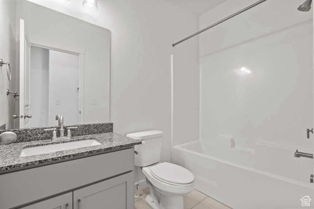 Full bathroom with toilet, vanity, tile patterned flooring, and washtub / shower combination