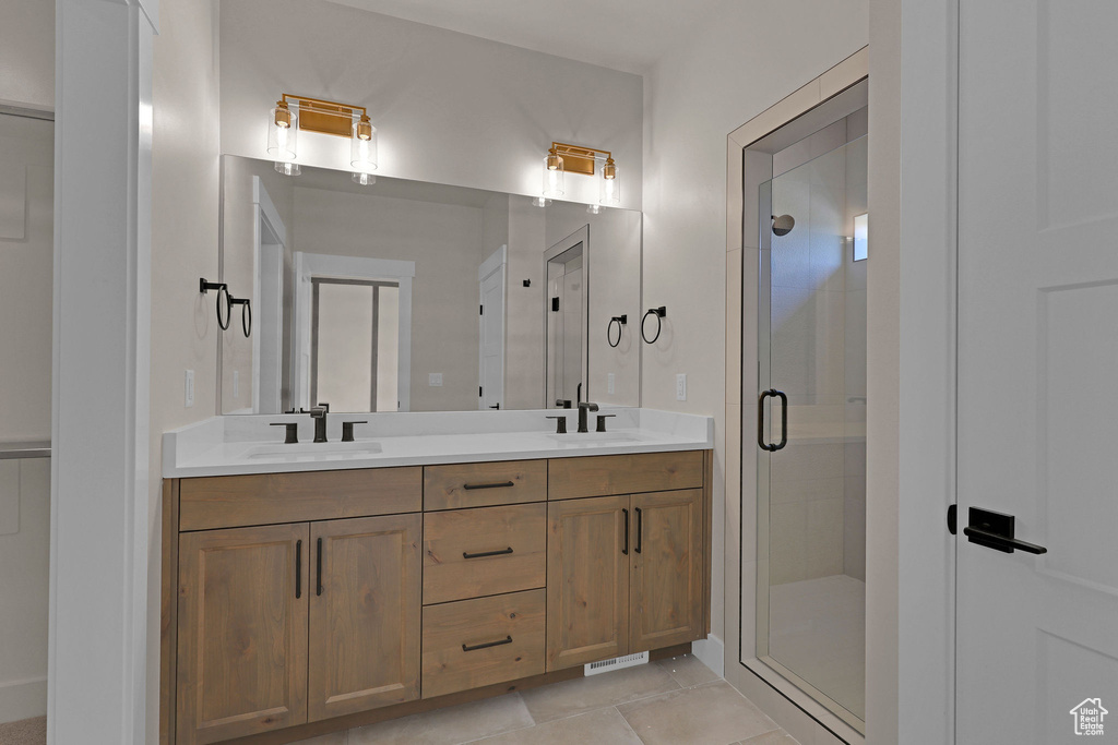 Full bath with double vanity, a shower stall, and tile patterned flooring