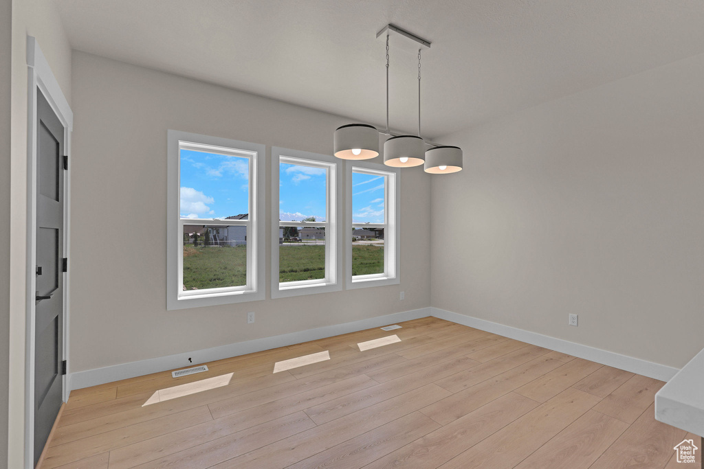 Unfurnished dining area with light wood-style flooring and baseboards