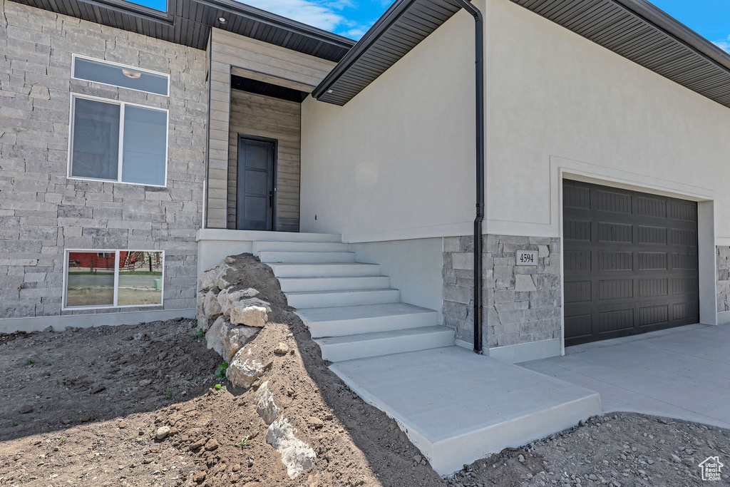 View of home\'s exterior featuring stone siding, a garage, and driveway
