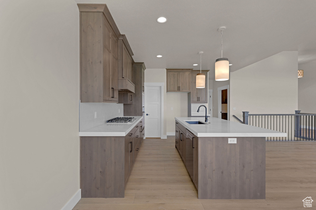 Kitchen featuring a sink, stainless steel gas stovetop, light wood finished floors, baseboards, and recessed lighting