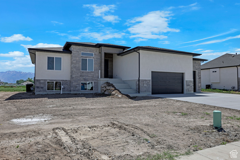 Prairie-style house featuring stone siding, driveway, an attached garage, and a mountain view
