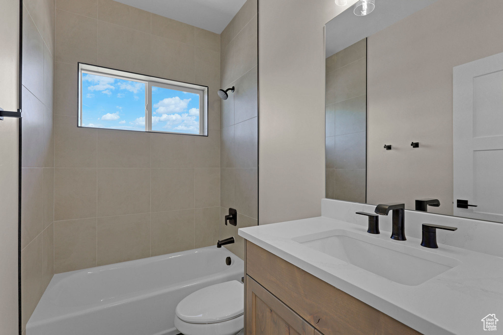Bathroom featuring vanity, toilet, and washtub / shower combination