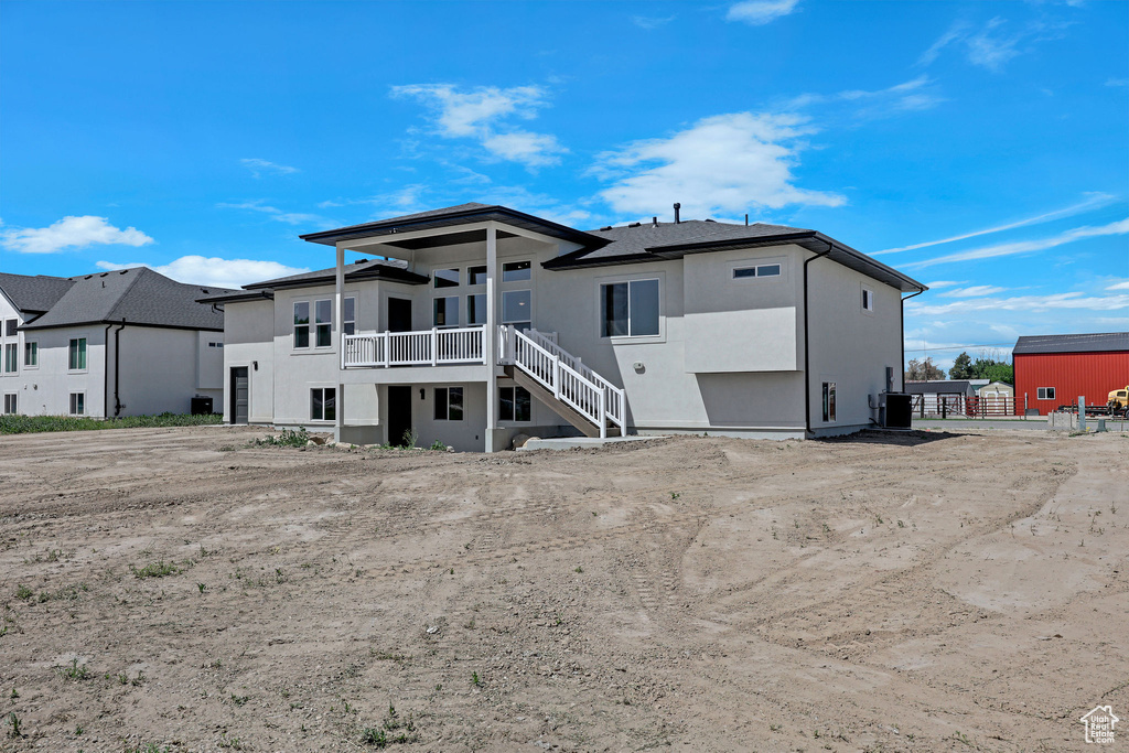 Rear view of property featuring stucco siding, central AC, and stairs