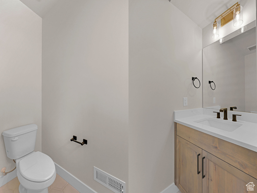Half bath with vanity, tile patterned flooring, toilet, and baseboards