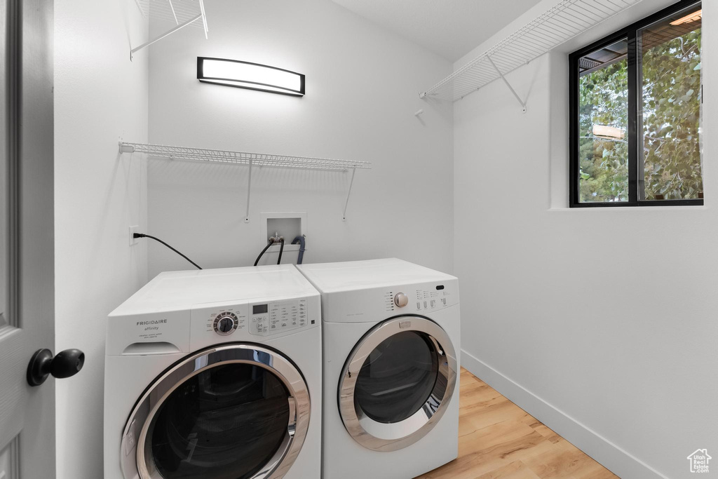 Laundry area featuring washing machine and dryer, wood finished floors, and baseboards