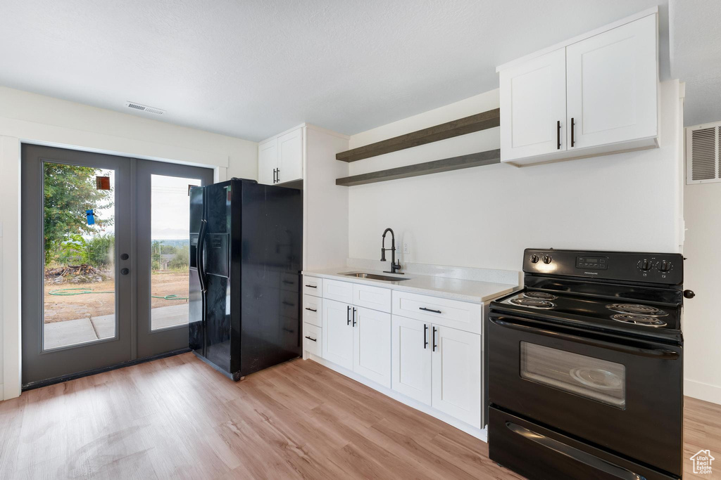 Kitchen with black appliances, open shelves, a sink, french doors, and white cabinetry