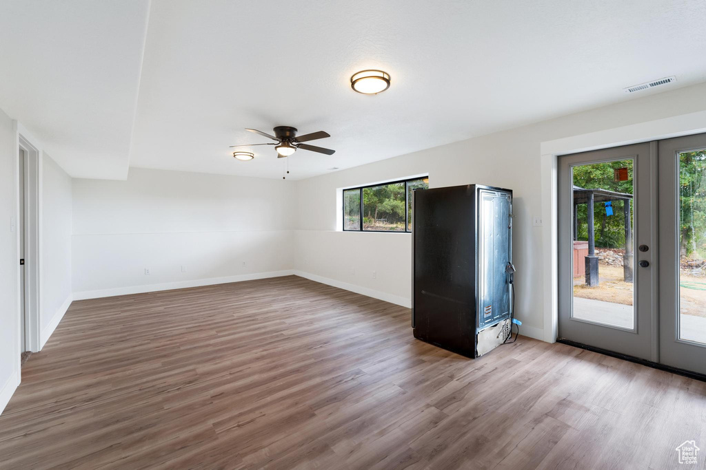 Spare room featuring french doors, baseboards, a ceiling fan, and wood finished floors