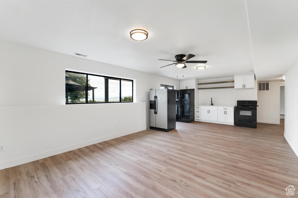 Unfurnished living room with light wood finished floors, ceiling fan, baseboards, and a sink