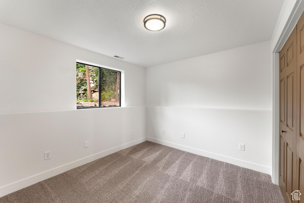 Carpeted empty room with baseboards and a textured ceiling