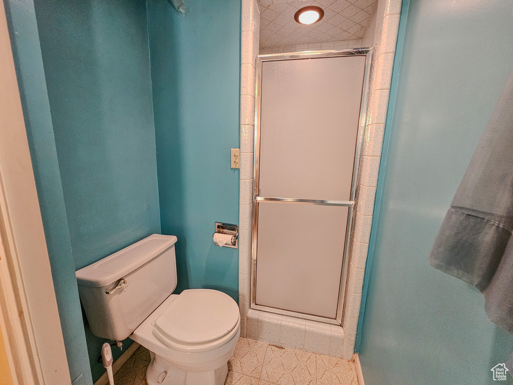 Bathroom featuring toilet, a shower stall, and baseboards