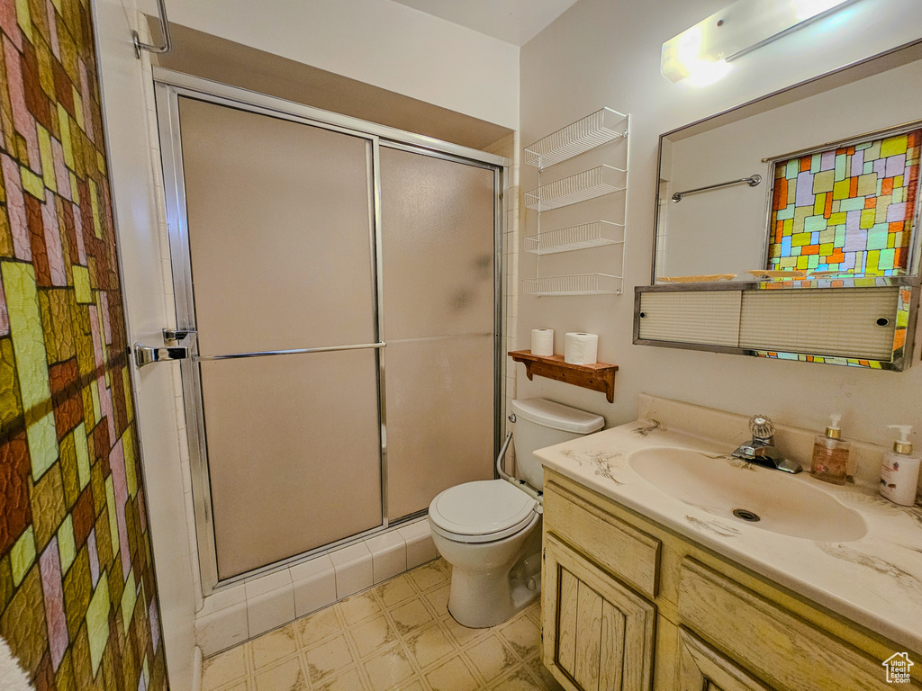 Bathroom with a shower stall, toilet, vanity, and tile patterned floors