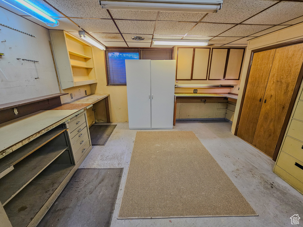 Kitchen with open shelves, a paneled ceiling, and concrete flooring