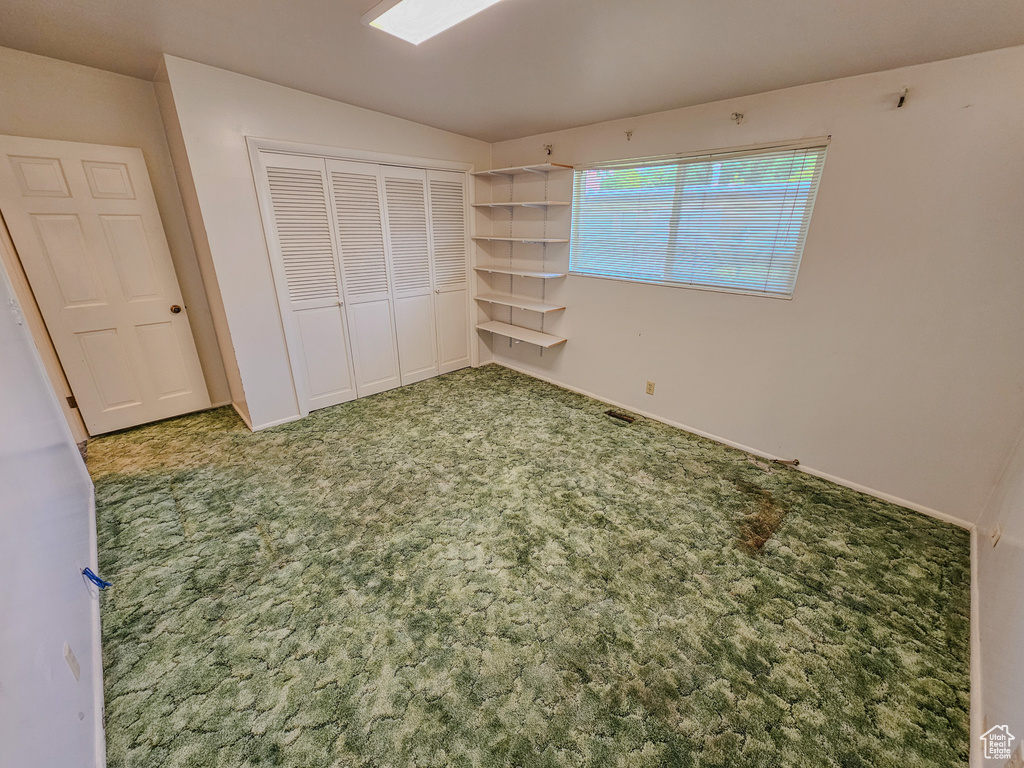 Unfurnished bedroom with carpet, a closet, and baseboards