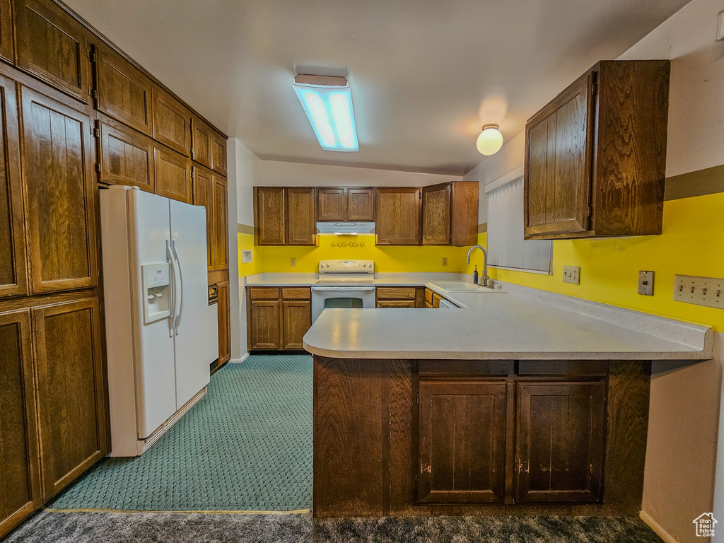 Kitchen with white appliances, a sink, under cabinet range hood, a peninsula, and light countertops