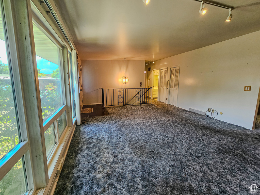 Carpeted spare room featuring track lighting
