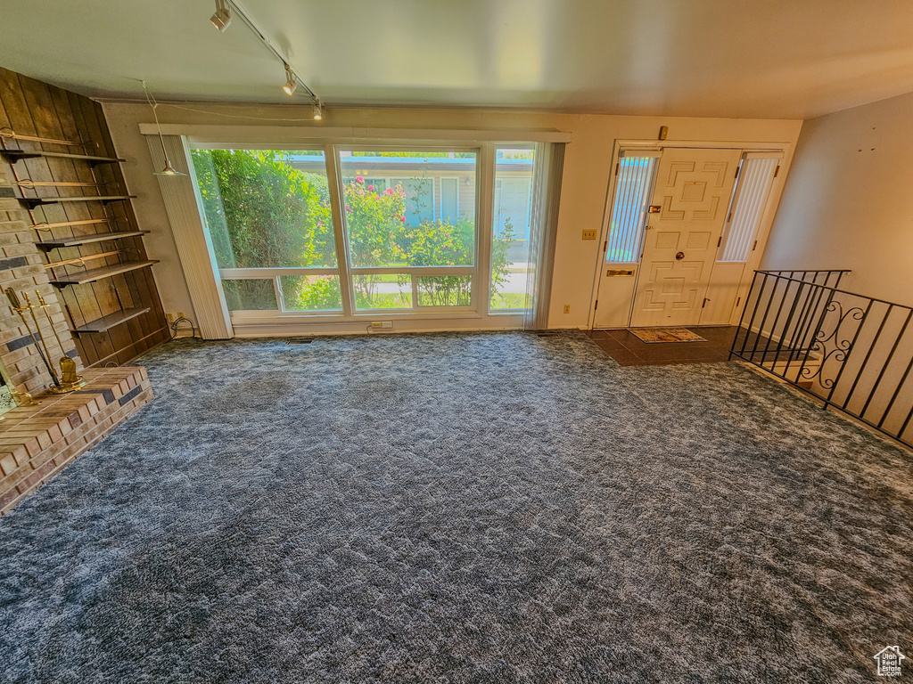 Unfurnished living room featuring carpet flooring and rail lighting