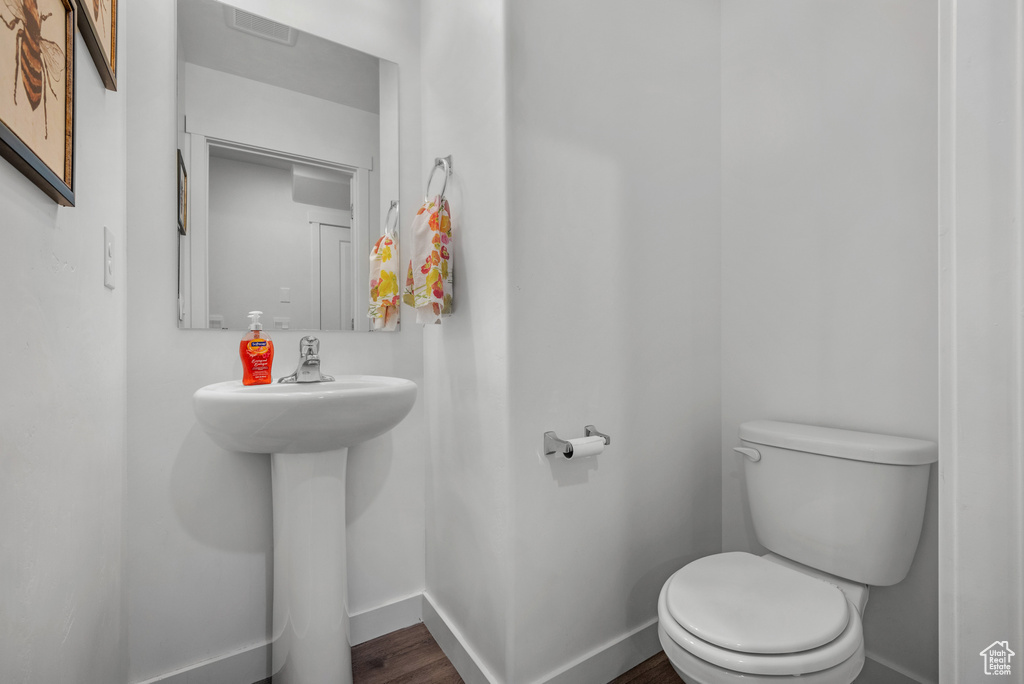 Bathroom with toilet, baseboards, and wood finished floors