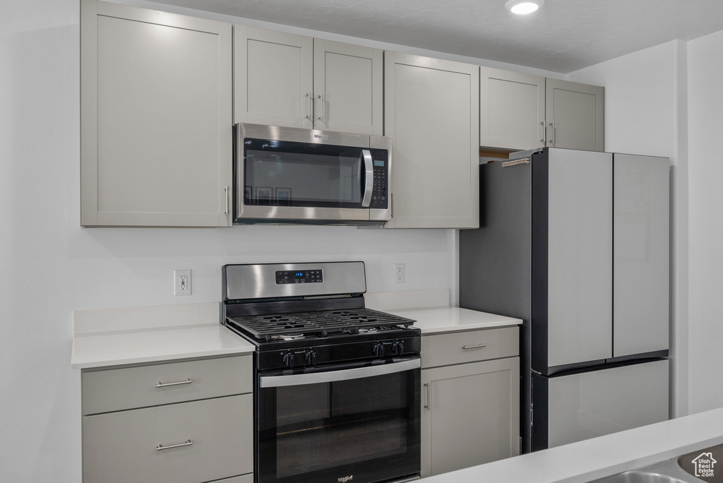 Kitchen with stainless steel appliances, gray cabinets, and light countertops