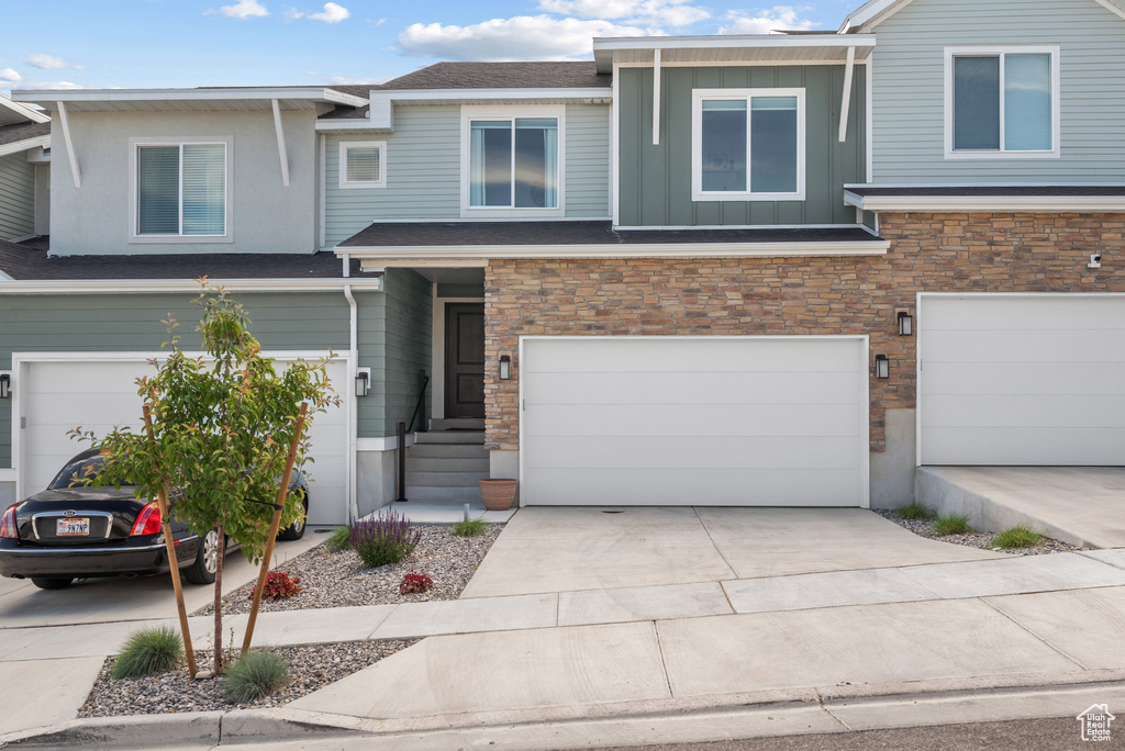 View of front of house featuring a garage, driveway, stone siding, and board and batten siding