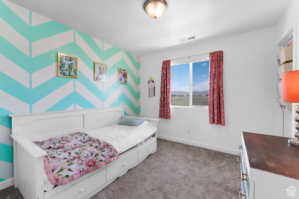 Carpeted bedroom featuring baseboards and a textured ceiling
