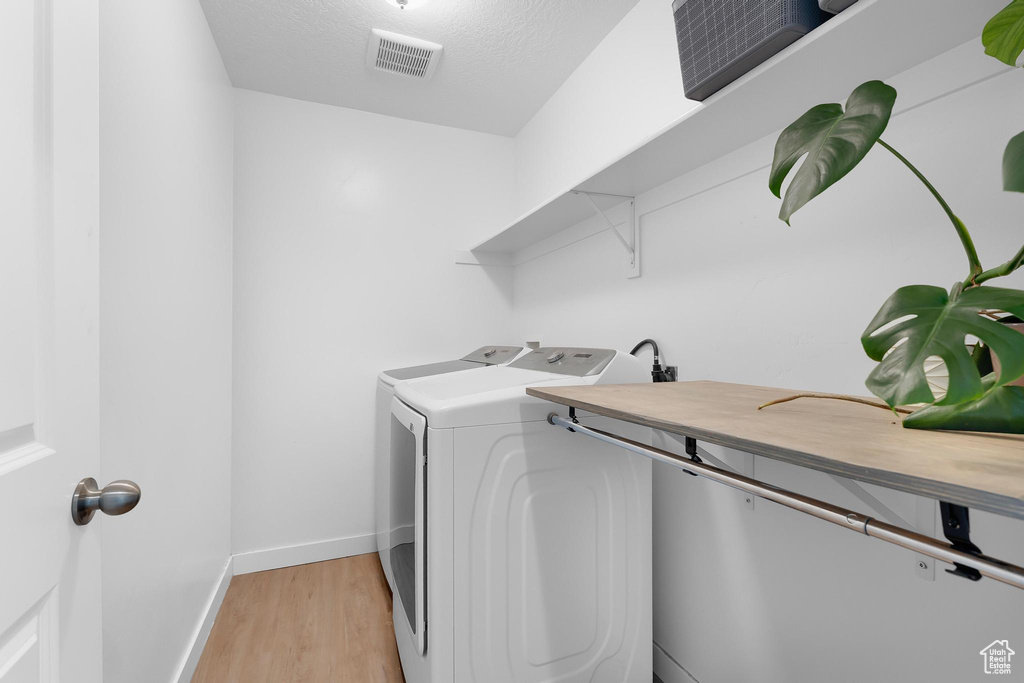 Laundry room featuring washing machine and clothes dryer, light wood finished floors, and baseboards