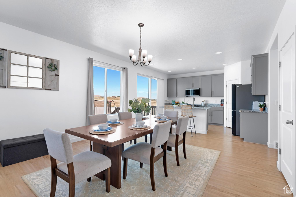 Dining room with a chandelier, light wood-style floors, recessed lighting, and baseboards