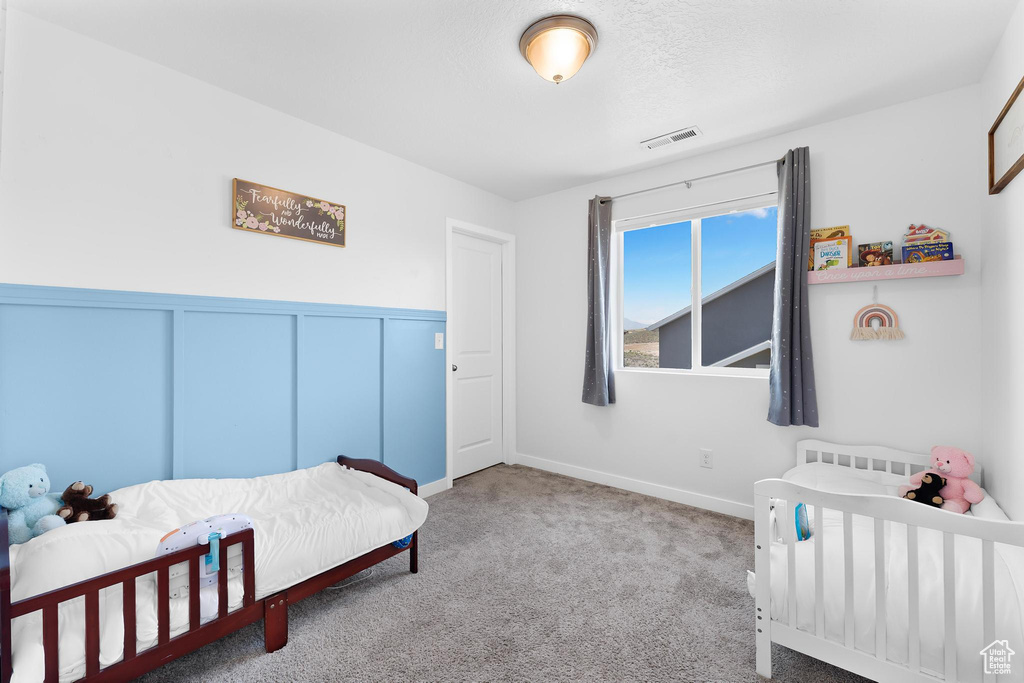 Carpeted bedroom with baseboards and wainscoting