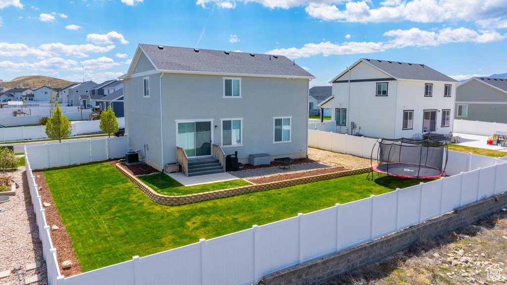 Back of property featuring a residential view, cooling unit, stucco siding, a trampoline, and entry steps