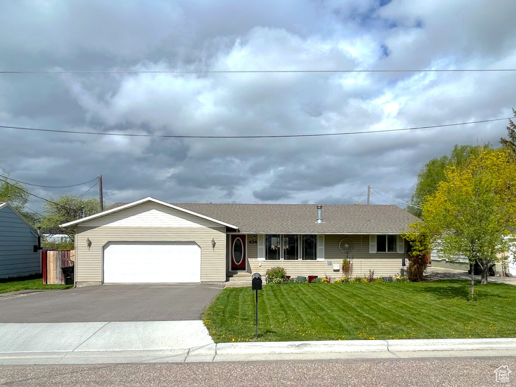 View of front facade with a front lawn, asphalt driveway, and a garage