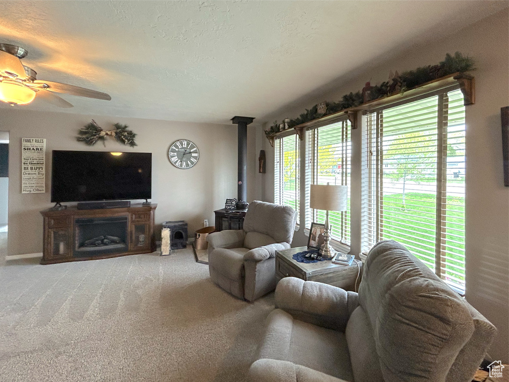 Carpeted living room with a wood stove and ceiling fan