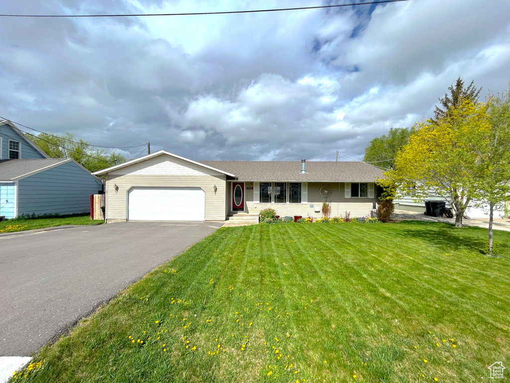 Ranch-style home with an attached garage, driveway, and a front yard