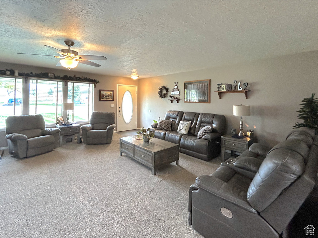 Carpeted living area featuring ceiling fan and a textured ceiling