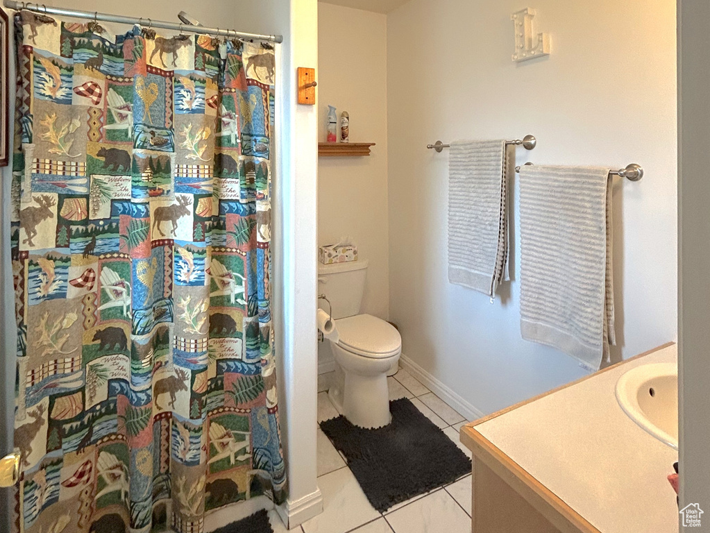 Bathroom featuring toilet, vanity, tile patterned floors, a shower with shower curtain, and baseboards