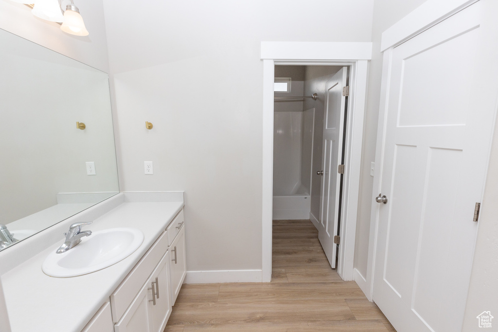 Bathroom featuring vanity, wood finished floors, baseboards, and a shower