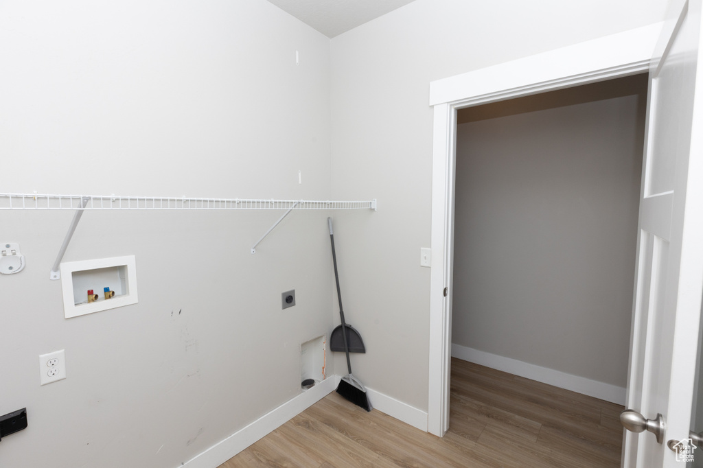 Washroom with electric dryer hookup, light wood-type flooring, gas dryer hookup, washer hookup, and baseboards