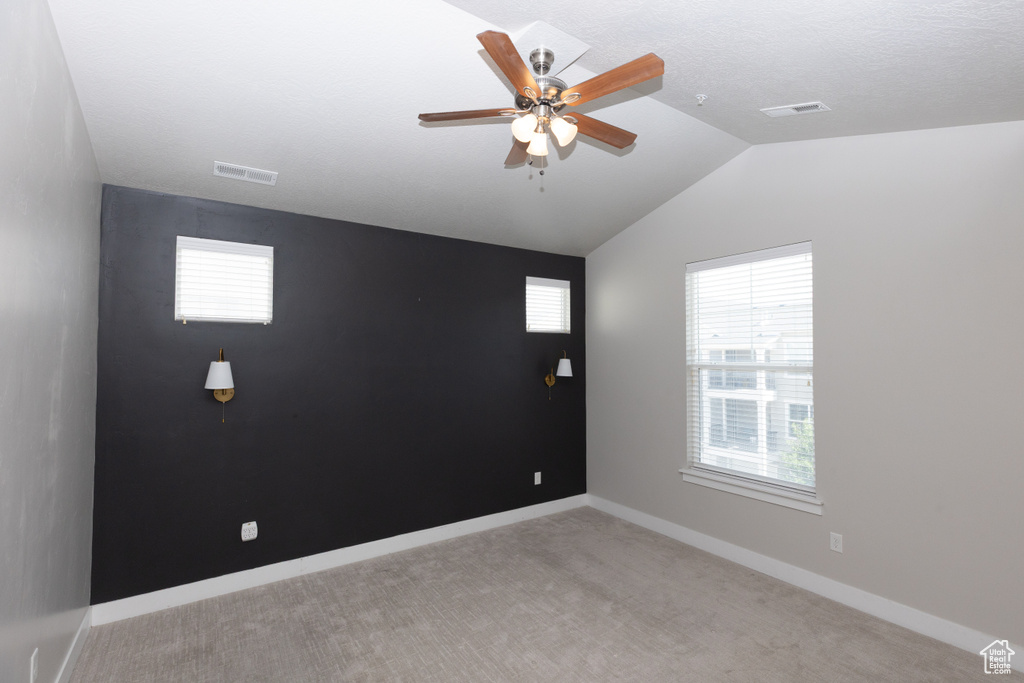Carpeted empty room with lofted ceiling, ceiling fan, and baseboards