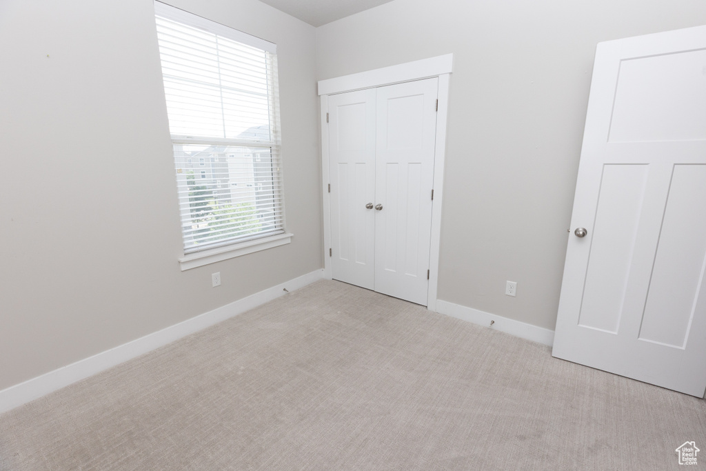 Unfurnished bedroom featuring carpet floors, baseboards, and a closet