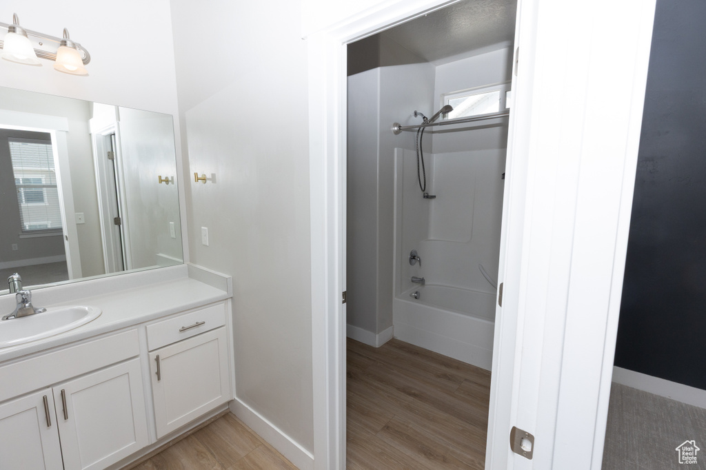 Bathroom featuring vanity, wood finished floors, shower / bathtub combination, and baseboards